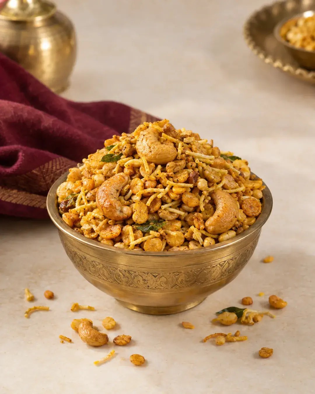 Kaju dalmoth namkeen with fried lentils, sev and whole cashews in a brass bowl