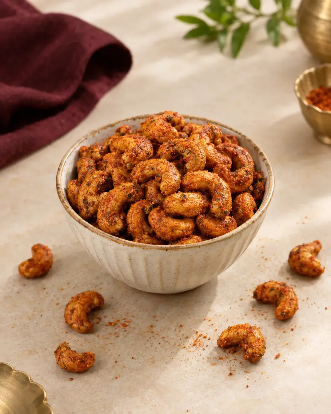 Roasted cashews coated in red masala spice in a ceramic bowl